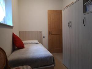 a bedroom with a bed with a red pillow and a door at Appartamento in Commezzadura