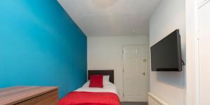 クルーにあるTownhouse @ Edleston Road Creweの青い壁のベッドルーム1室、赤い枕付きのベッド1台が備わります。