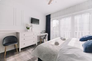 a white bedroom with a desk and a bed at Zwierzyńscy Residence 2 in Pobierowo