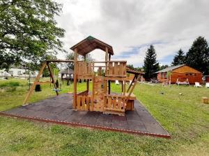 a playground in a field with a wooden play structure at Fortuna Apartmanházak in Bogács