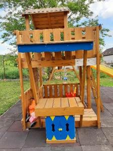 a playground with a wooden bench and a play structure at Fortuna Apartmanházak in Bogács