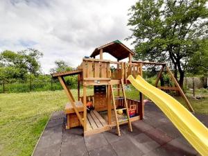 a wooden play structure with a slide and a playground at Fortuna Apartmanházak in Bogács