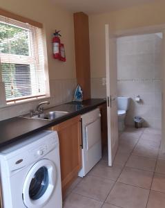 a kitchen with a washing machine and a sink at Foleys Ardmullen Manor Houses in Kenmare