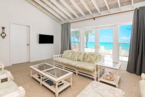 a living room with a couch and a view of the ocean at Beachfront White Palm Villa- Tar Bay, Great Exuma in Rokers Point Settlement