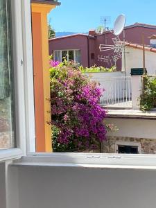 a window with a bush of purple flowers on a balcony at Affittacamere Benedetta e Isabelle in Vernazza