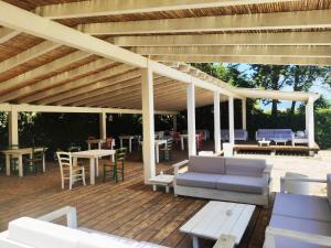 a wooden deck with a pergola and tables and chairs at Is Benas Country Lodge in San Vero Milis