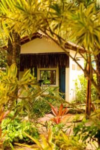 uma casa com uma porta azul num jardim em Na Villa dos Algodões em Maraú