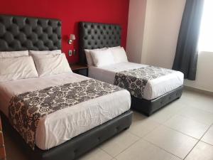 um quarto com 2 camas e uma parede vermelha em Hotel Jar8 Acuario enfrente al Acuario de Veracruz em Veracruz