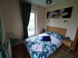 Un dormitorio con una cama con sábanas azules y una ventana. en M&K Apartament Słoneczna Wyspa - Sobieszewo, Wyspa Sobieszewska, en Gdansk