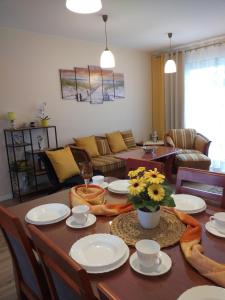 Una sala de estar con una mesa con platos y flores. en M&K Apartament Słoneczna Wyspa - Sobieszewo, Wyspa Sobieszewska, en Gdansk 20 fotos más