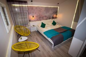 a bedroom with a bed and two yellow chairs at Hotel Villa Nadin in Mostar