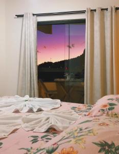 een slaapkamer met een bed en uitzicht op de zonsondergang bij Pousada Costa dos Corais in Mangaratiba