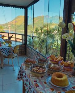 a table with baskets of bread on it with a view at Pousada Costa dos Corais in Mangaratiba