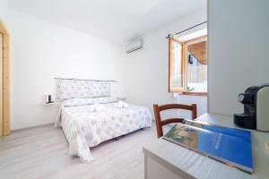 a white bedroom with a bed and a window at Brezza B&B in Golfo Aranci