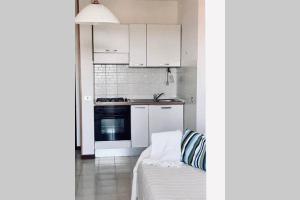 una cucina con armadi bianchi e un divano in camera di Bilocale vista mare a Fano