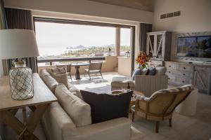 - un salon avec un canapé, des chaises et une grande fenêtre dans l'établissement Esperanza, Auberge Resorts Collection, à Cabo San Lucas