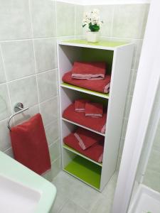 a white shelf with red towels in a bathroom at Chiara Naxos Apartment in Giardini Naxos +40 photos