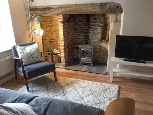 a living room with a brick fireplace and a tv at Troopers Cottage in Frome