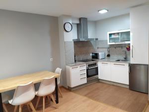 a kitchen with a wooden table and white cabinets at Apartamento F6 in Marín