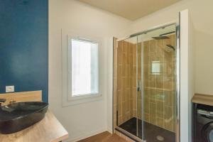 a bathroom with a sink and a glass shower at L'urbain Narbonnais in Narbonne