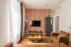 a living room with a couch and a brick wall at L'urbain Narbonnais in Narbonne