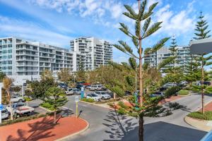 an apartment complex with a pine tree in a parking lot at Studio 11 Mandurah Marina in Mandurah