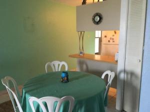 a dining room with a green table and white chairs at Caguax 206 in Cabo Rojo