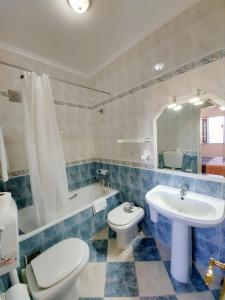 a bathroom with a toilet and a sink and a tub at VILA FORMOSA AL-Estabelecimento de Hospedagem,Quartos-Rooms in Monte Gordo