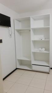 um armário branco com prateleiras brancas e uma televisão em Hotel Casa Blanca em Campina Grande