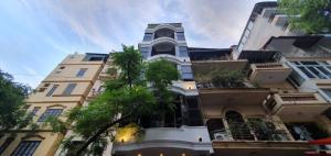 een hoog gebouw met bomen ervoor bij WIN HOTEL in Hanoi