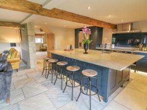 a kitchen with a blue island with bar stools at The Old Shippon in Keighley