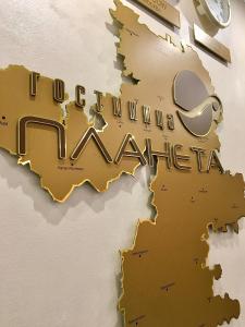 una señal de oro en una pared con las palabras Universidad de syracuse en Planeta Hotel, en Chelyabinsk