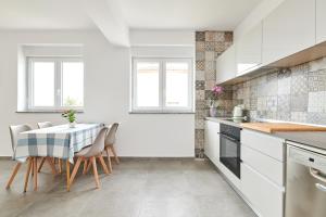 una cocina blanca con mesa y sillas. en Apartmani Ivana, en Umag