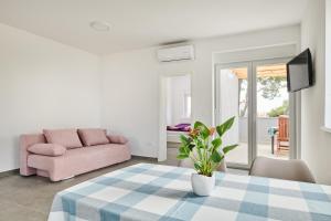 a living room with a table and a pink couch at Apartmani Ivana in Umag