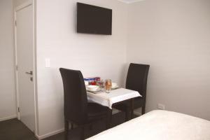 a dining room table with two chairs and a tv on the wall at The Birch Tree B&B in Motueka