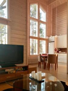 een woonkamer met een flatscreen-tv en een tafel bij KolinPilvi in Kolinkylä