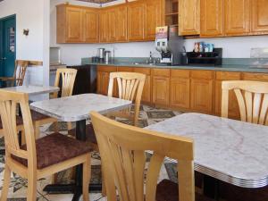 una cocina con armarios de madera, mesas y sillas en Quality One Motel, en Weatherford