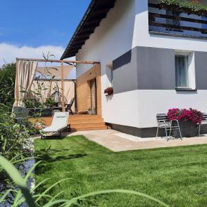 una casa con un cortile verde con una sedia e un patio di pogodnawilla a Mielno Altre 40 foto