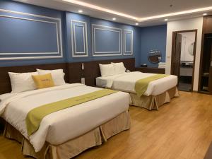2 łóżka w pokoju hotelowym z niebieskimi ścianami w obiekcie Hotel Villa Ju w mieście Hanoi