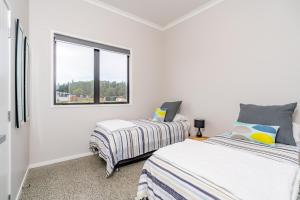 two beds in a white room with a window at Northcoast Getaway in Mangawhai