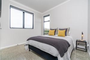 a white bedroom with a large bed with yellow pillows at Northcoast Getaway in Mangawhai +6 photos