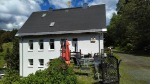 a white house with a black roof and a table and chairs at Greizer Kammhütte Gaststätte & Pension in Klingenthal