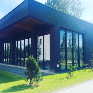 a building with glass windows and a tree in the grass at Apartament Sianożęty in Sianozety