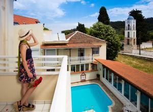 een vrouw op een balkon met uitzicht op een zwembad bij Philoxenia Inn in Limenas