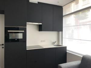 a kitchen with black cabinets and a sink and a window at FLORIDE in Knokke-Heist