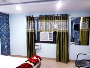 a bedroom with green curtains and a window at Kartar Yatri Niwas in Kānpur