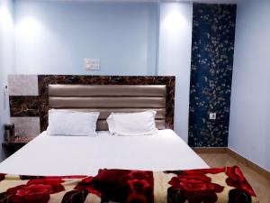 a bedroom with a large white bed with red flowers on the floor at Kartar Yatri Niwas in Kānpur