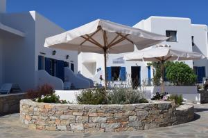 a stone wall with two umbrellas in front of a building at Paraporti in Chora Folegandros