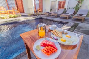a table with fruit and juice next to a swimming pool at Cening Ayu Sanur in Sanur