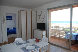ein Wohnzimmer mit einem weißen Tisch und einem Balkon in der Unterkunft Appartement Belle Vue in Valras-Plage